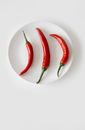 Three Cayenne Peppers on a White Saucer