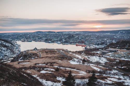 Snowy hills and lake against sunset sky in town