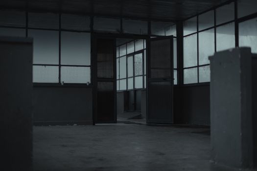 Interior of spacious empty room of gloomy abandoned building with glass windows and opened door