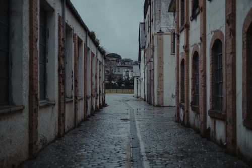 Free Empty narrow wet walkway between old shabby buildings in town street in daylight under gray sky Stock Photo