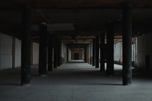 Perspective view of dark empty large hall of old building with columns and sunbeams coming in