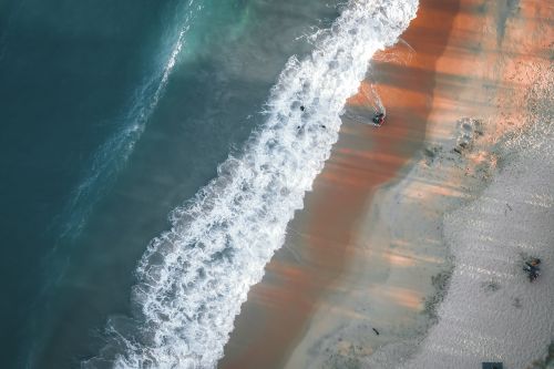 Free A captivating aerial shot of Terengganu's coastline showcasing vibrant waves and sandy shores at sunset. Stock Photo