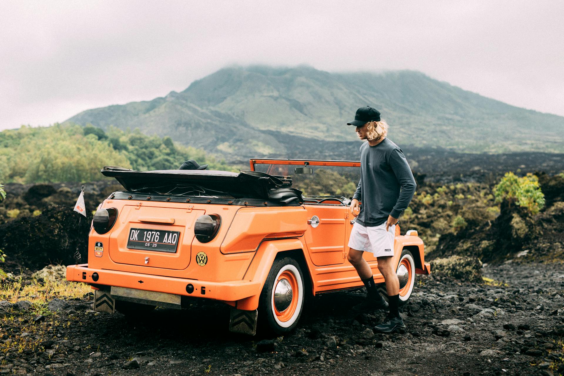 A Man in Gray Sweater Standing Beside the Top Down Car