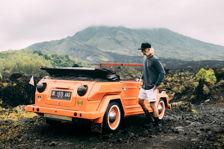 A Man In Gray Sweater Standing Beside The Top Down Car