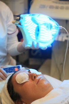 Close-up of a woman undergoing an LED light therapy facial at a spa. 