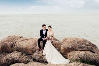 Bride and Groom Standing on Brown Rock Formation