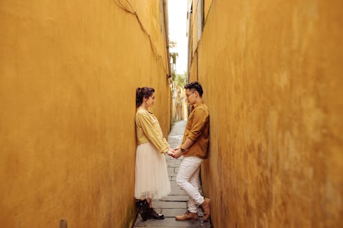 Free Couple Standing in an Alley Facing Each Other while Holding Hands Stock Photo