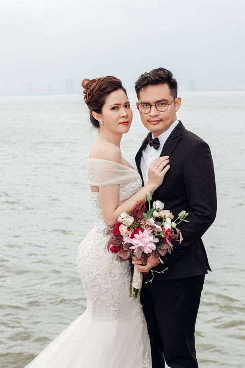 Free Bride and groom embrace by the sea in Da Nang, Vietnam, showcasing love and elegance. Stock Photo