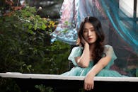Woman in Lace Dress Sitting Beside Plants