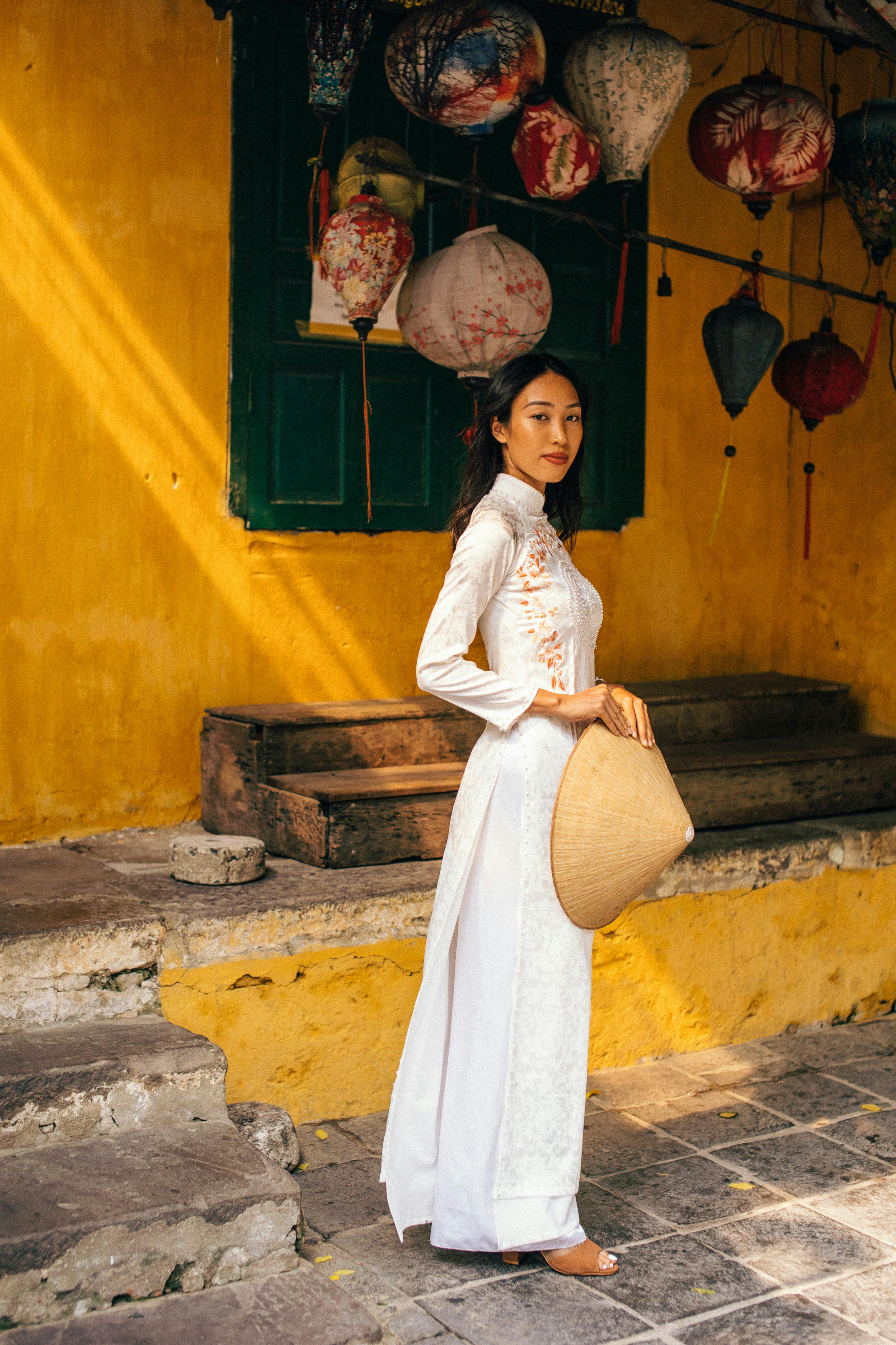 a woman wearing a white dress holding a conical hat