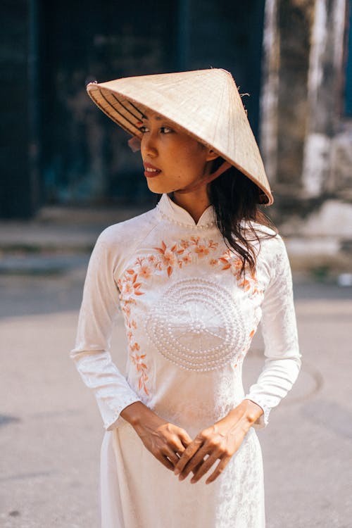 Woman in Traditional Dress and a Conical Hat Standing