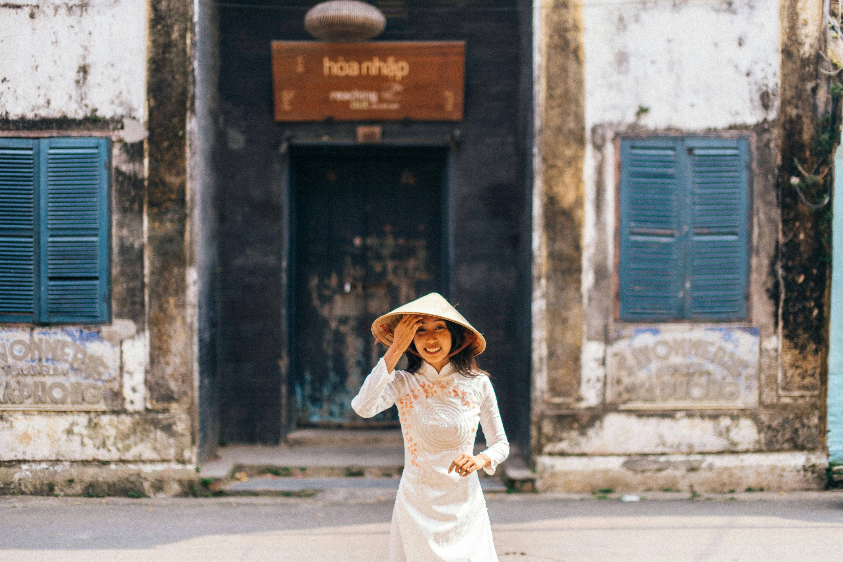 woman wearing a conical hat standing on a street