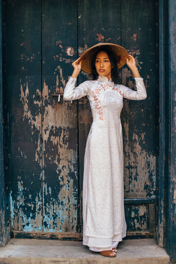 A Woman Wearing A White Dress And A Conical Hat