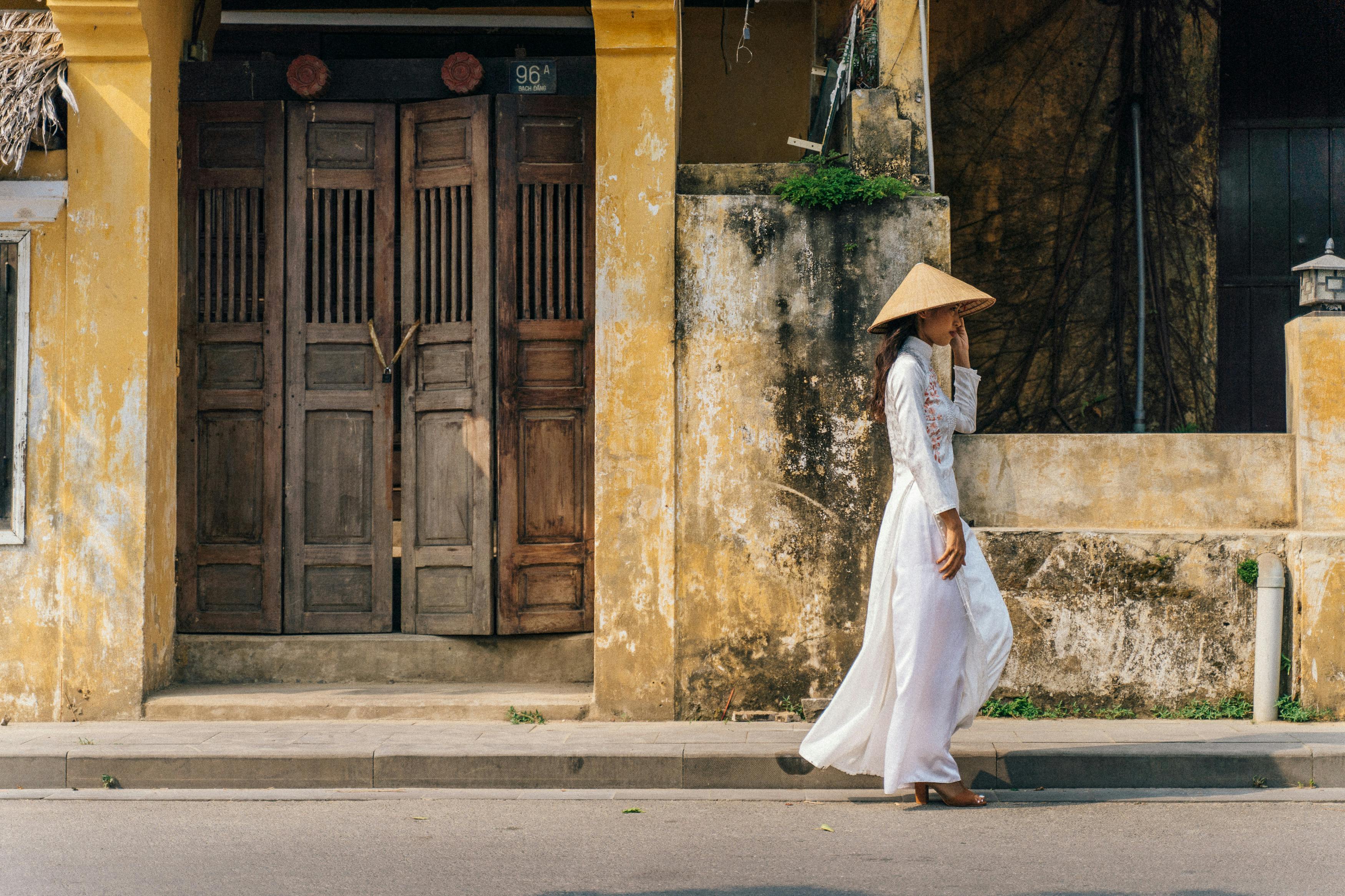 a side view of a woman in white dress walking on the street