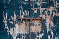 一扇质朴、风化的门的特写，油漆剥落，铁闩