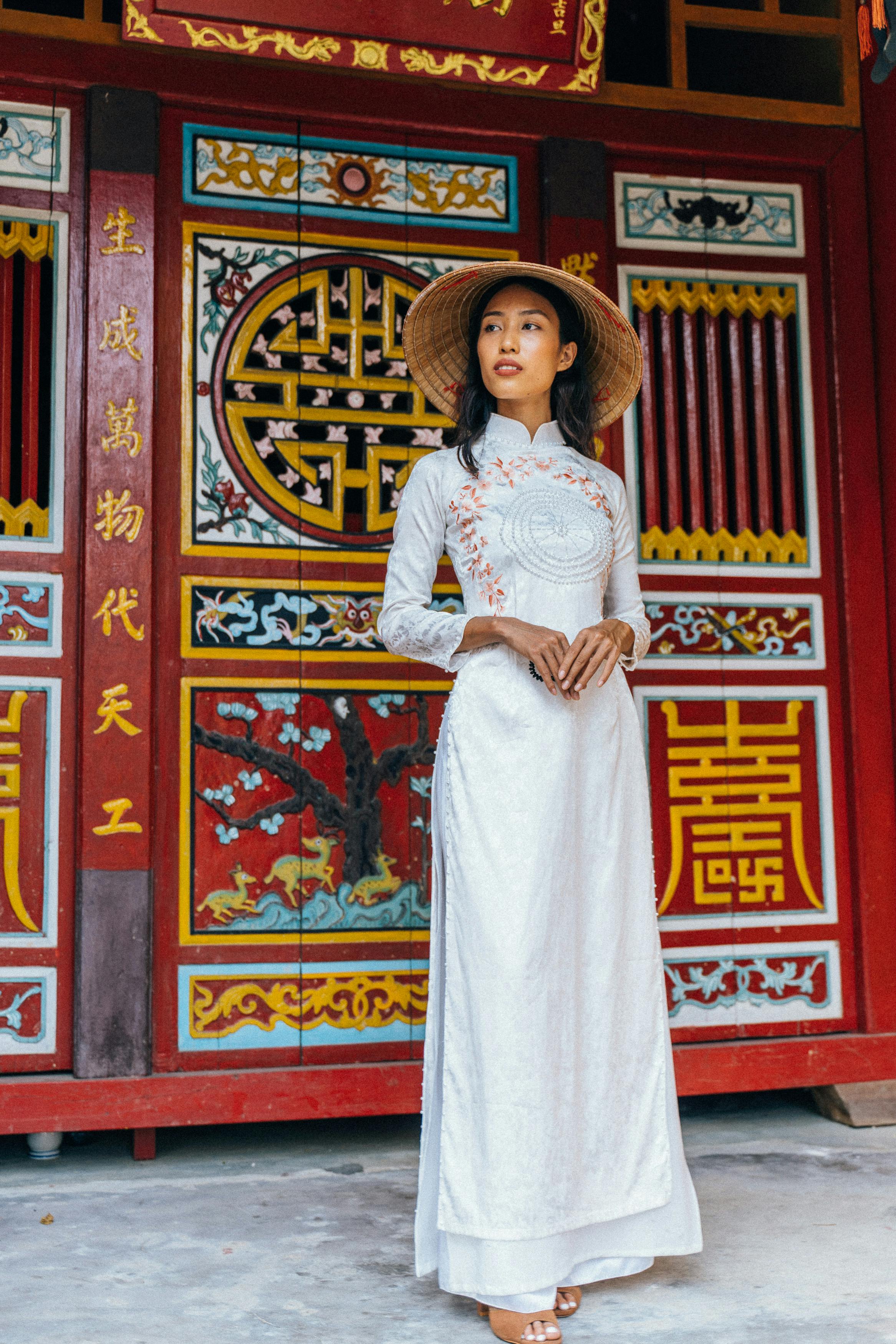 a woman in white traditional dress wearing conical hat