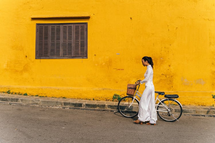 A Woman In White Ao Dai Walking With A Bicycle