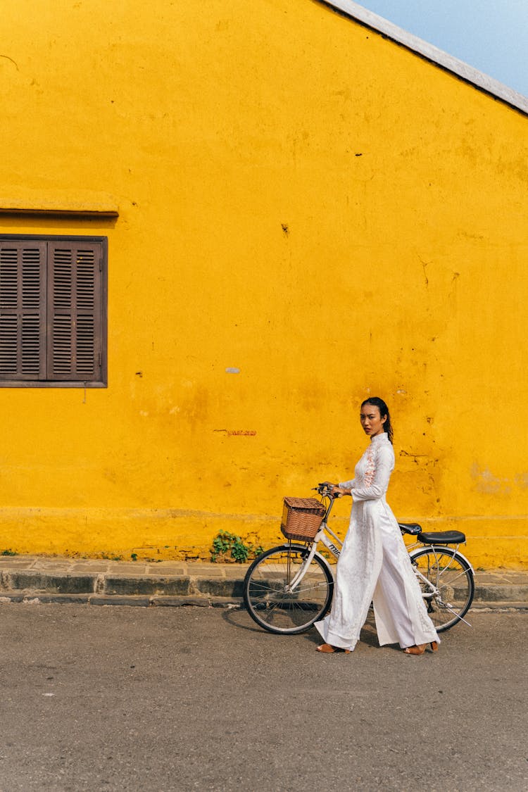 A Woman In White Ao Dai Walking With A Bicycle
