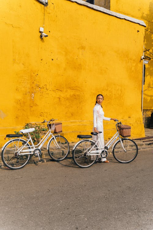 Ethnic woman standing with bicycle in city