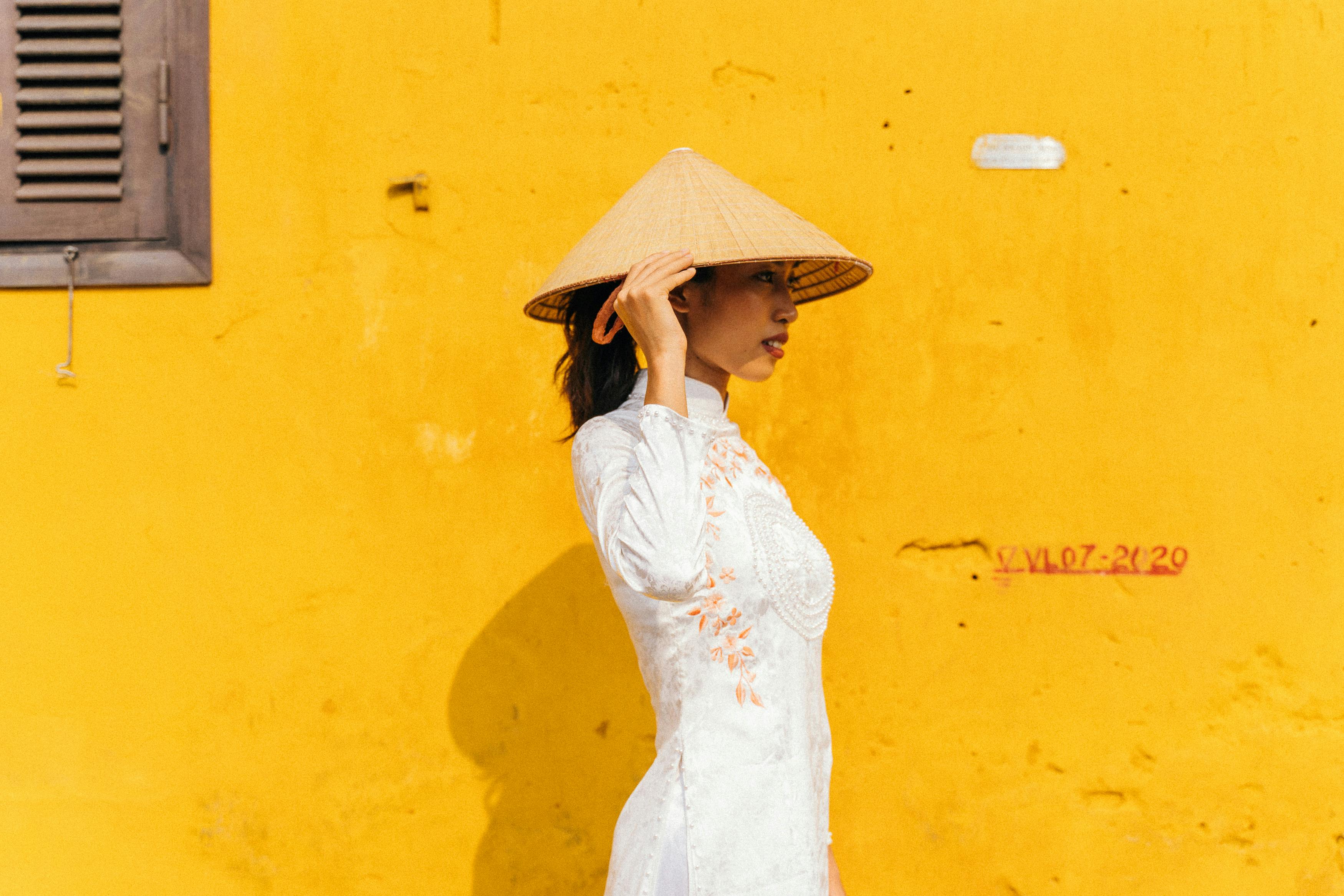 a woman in white ao dai wearing conical hat