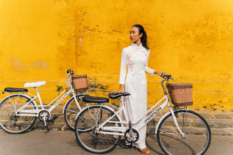 Woman In White Ao Dai Standing On Road With A Bicycle