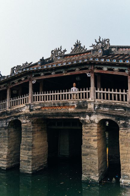 A serene view of the historic Japanese Covered Bridge in Hội An with a woman in traditional attire.