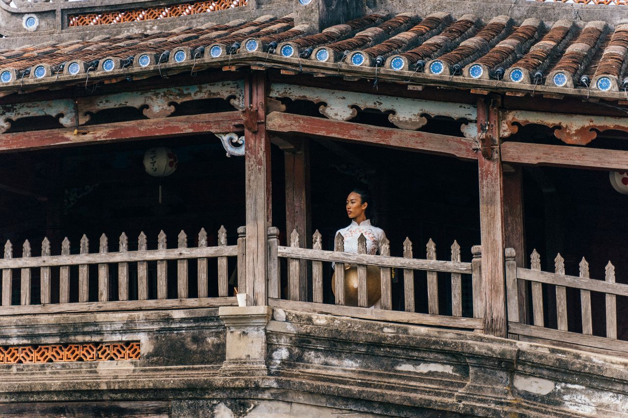 a woman in a traditional vietnamese ao dai stands gracefully on an anc