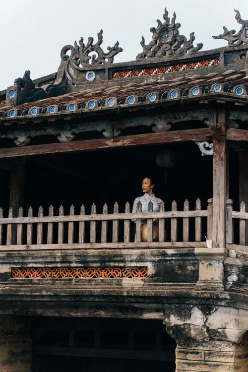 Free Woman in traditional Vietnamese dress standing on a historic balcony. Stock Photo