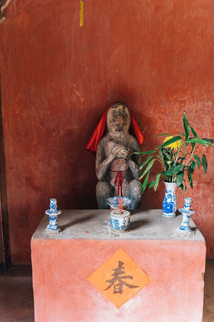 A serene Vietnamese shrine with an ancient statue, incense, and traditional decor.
