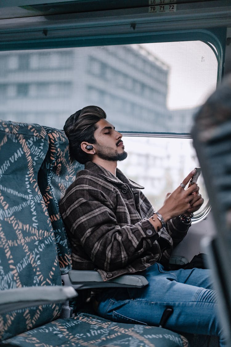 Bearded Man Sitting Inside A Bus Listening To Music