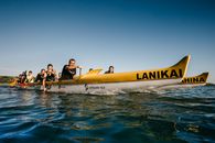 Unrecognizable athletes with oars in boats practicing canoeing sport on rippled lake under light sky