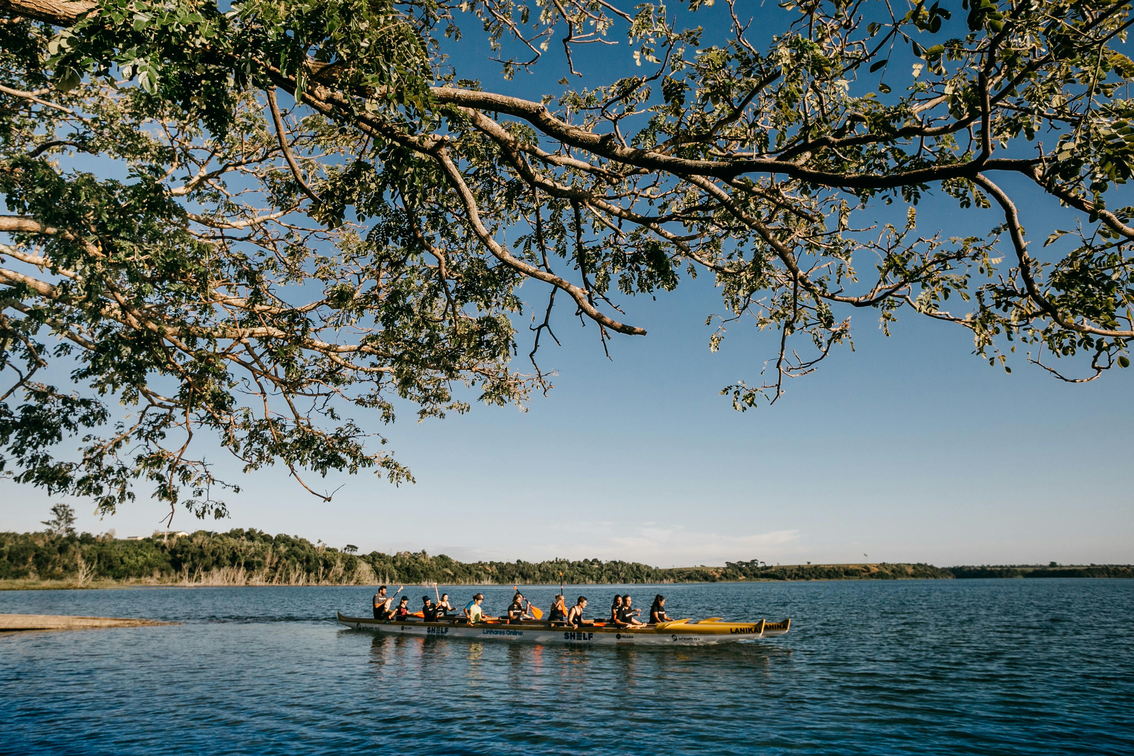 A group of people canoeing on a tranquil lake under a clear blue sky, surrounded by nature.