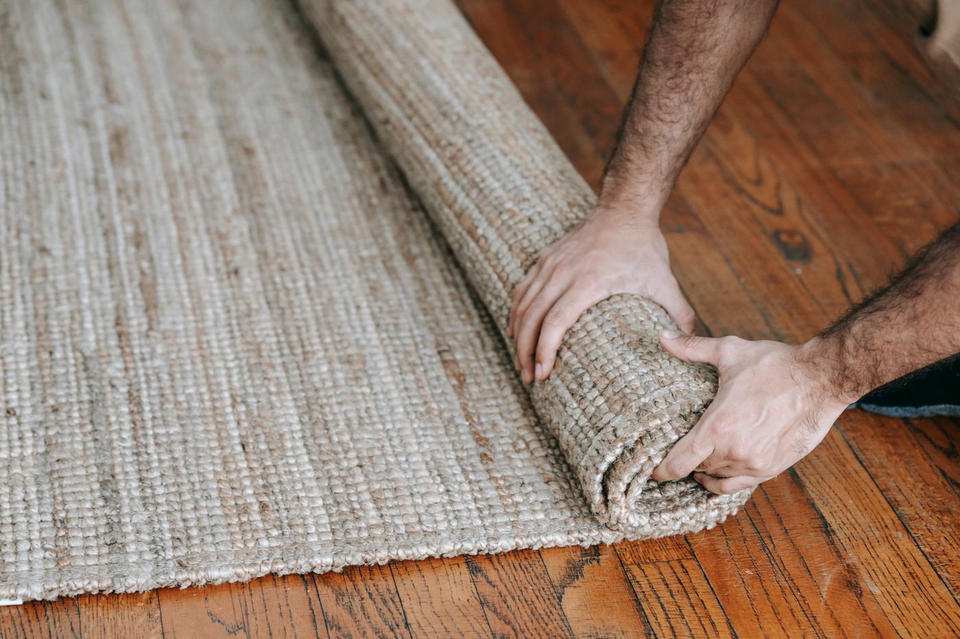 Person carefully rolling an area rug for cleaning or transport