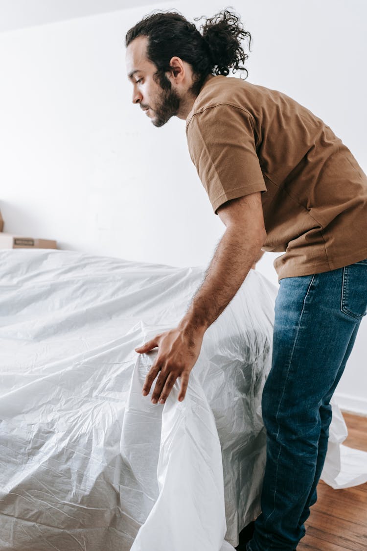 Man Covering A Couch With Linen