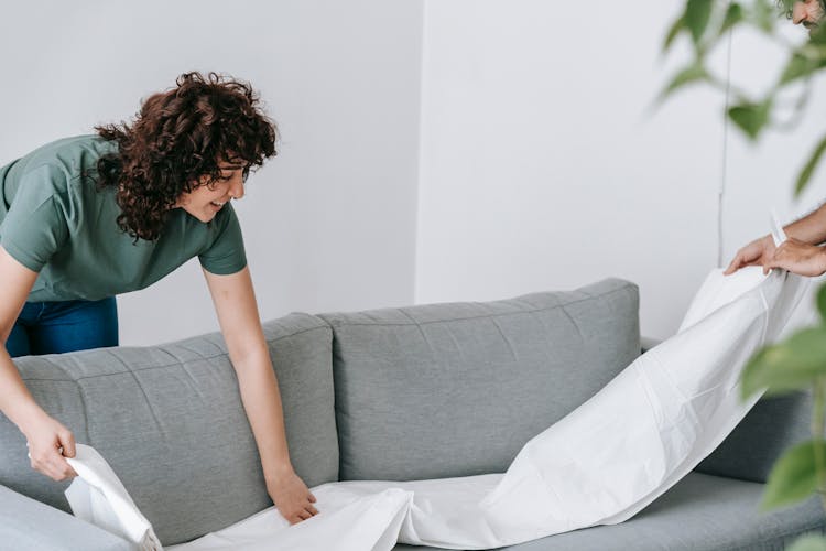 Woman Holding A White Linen To Cover The Couch