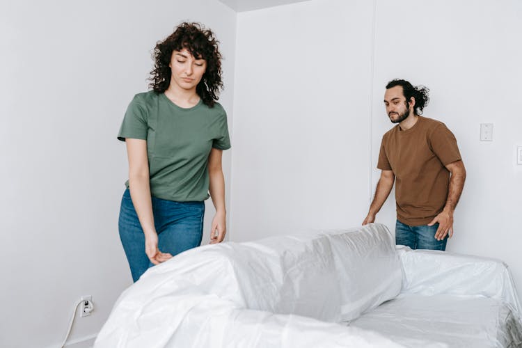 Couple Covering A Couch With Linen