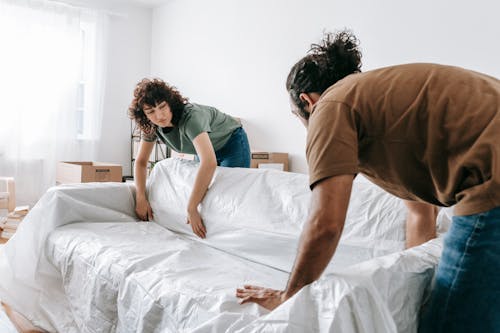 Couple Wrapping A Couch With White Cloth