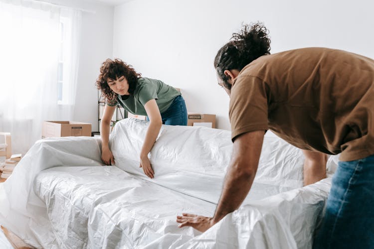 Couple Wrapping A Couch With White Cloth