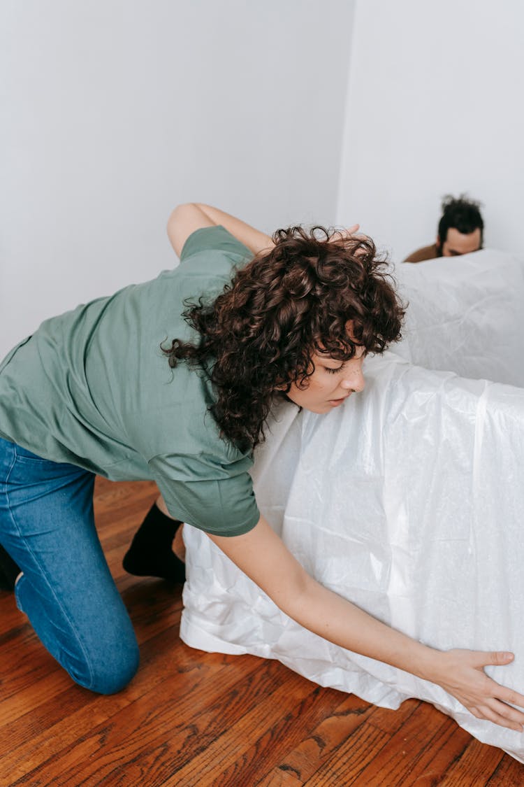 Couple Covering A Couch With White Cloth