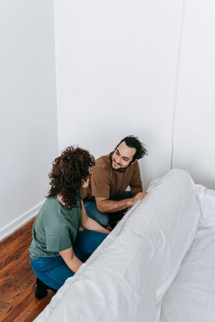 Couple Covering A Couch With Cloth