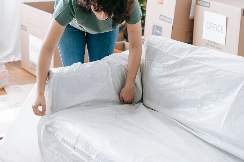 Crew wrapping a sofa in protective plastic before the lift