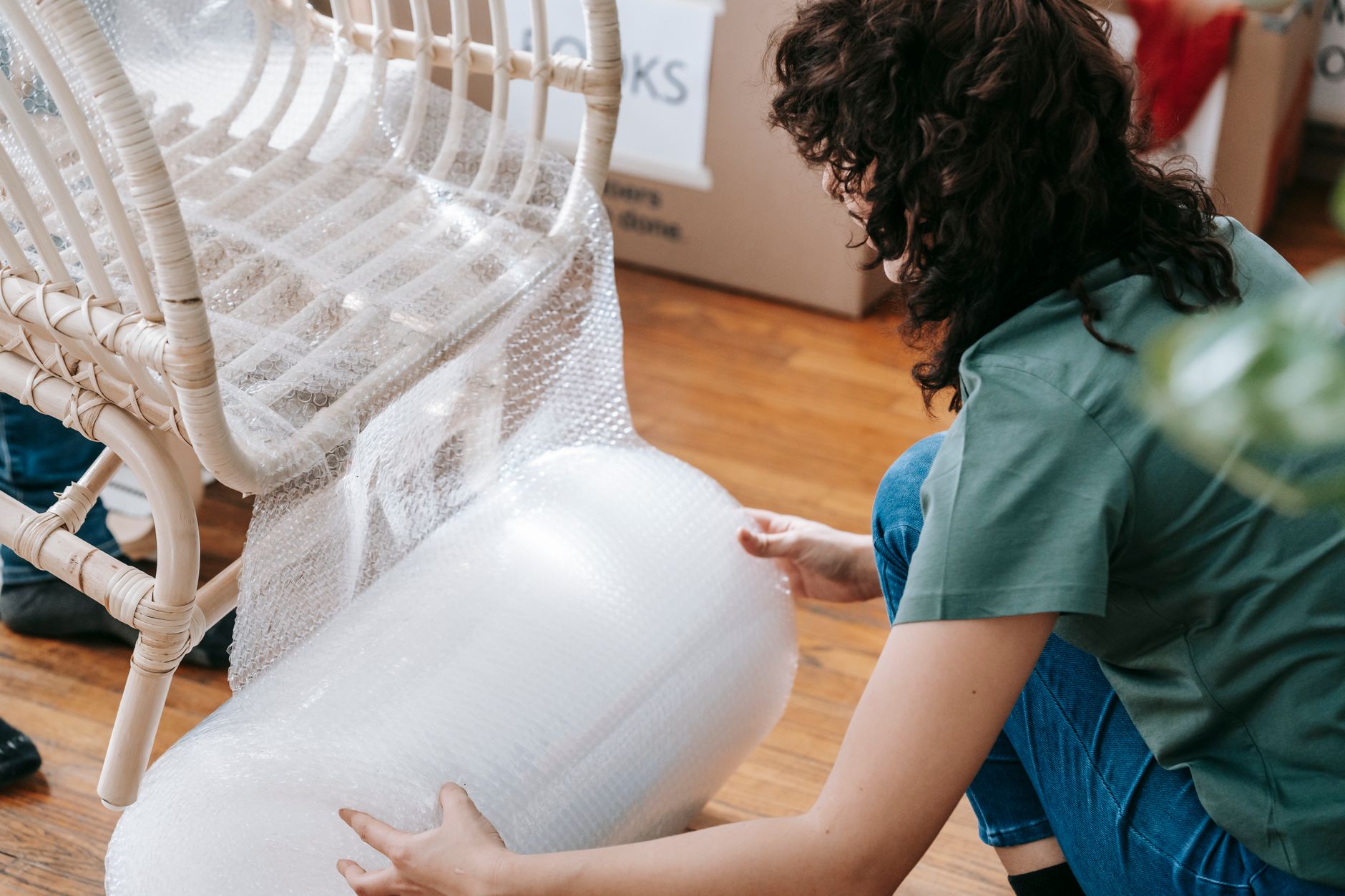 worker packing fragile product with bubble air cushions and kraft paper in shipping box