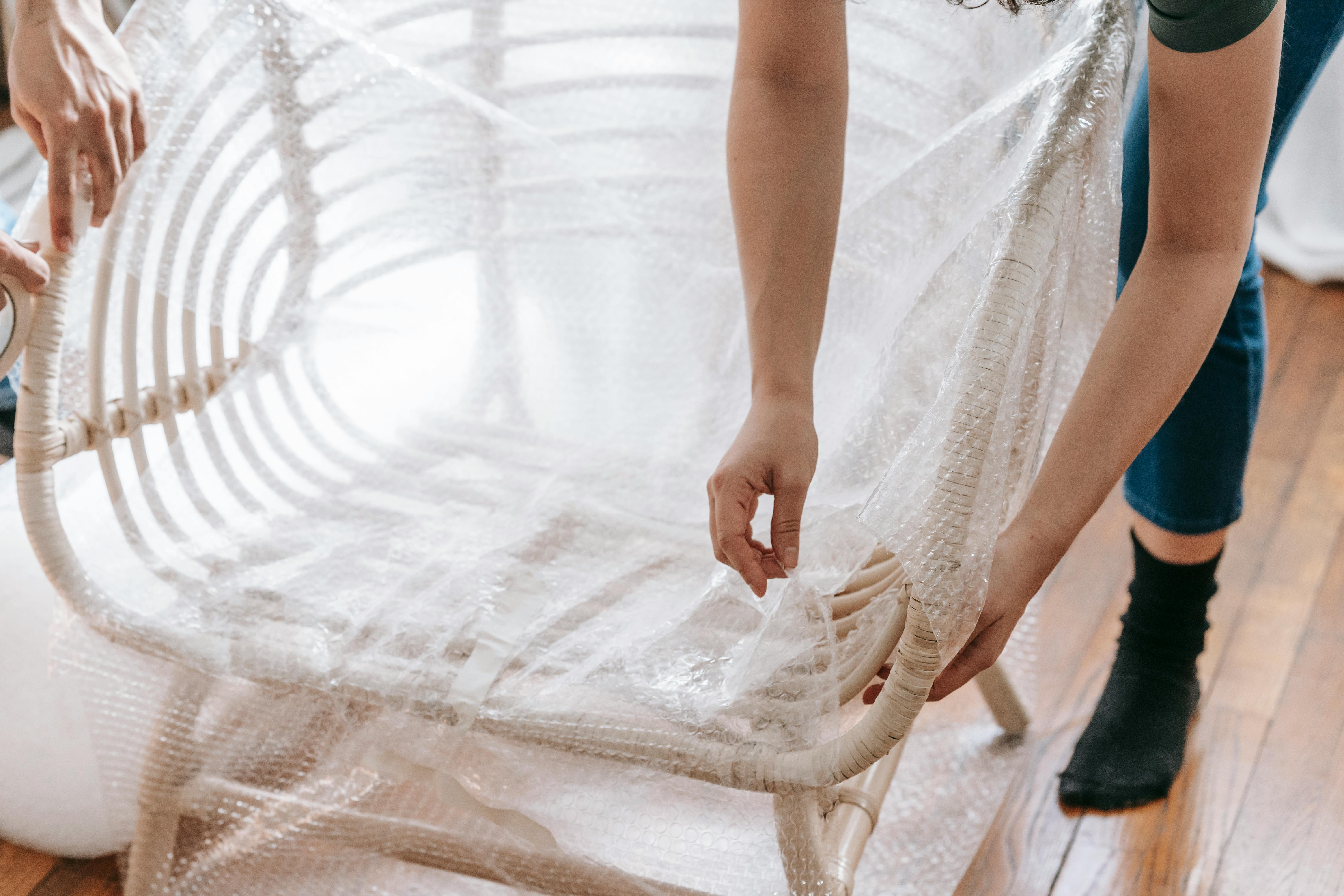 person wrapping a chair with plastic