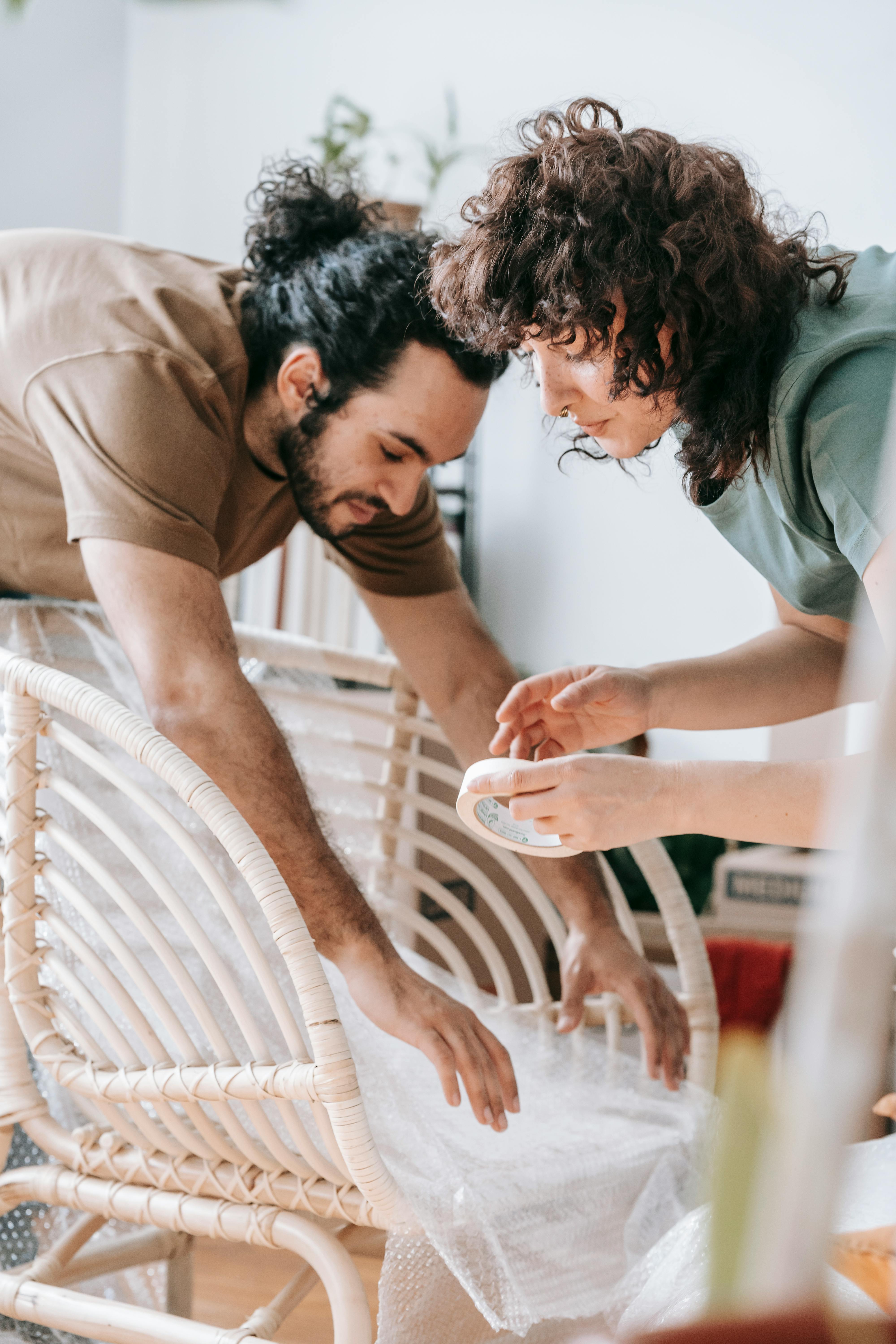 Couple Covering A Chair With Bubble Wrap · Free Stock Photo