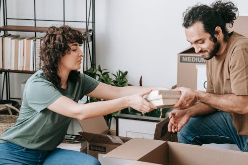 A Couple Packing Books In A Box