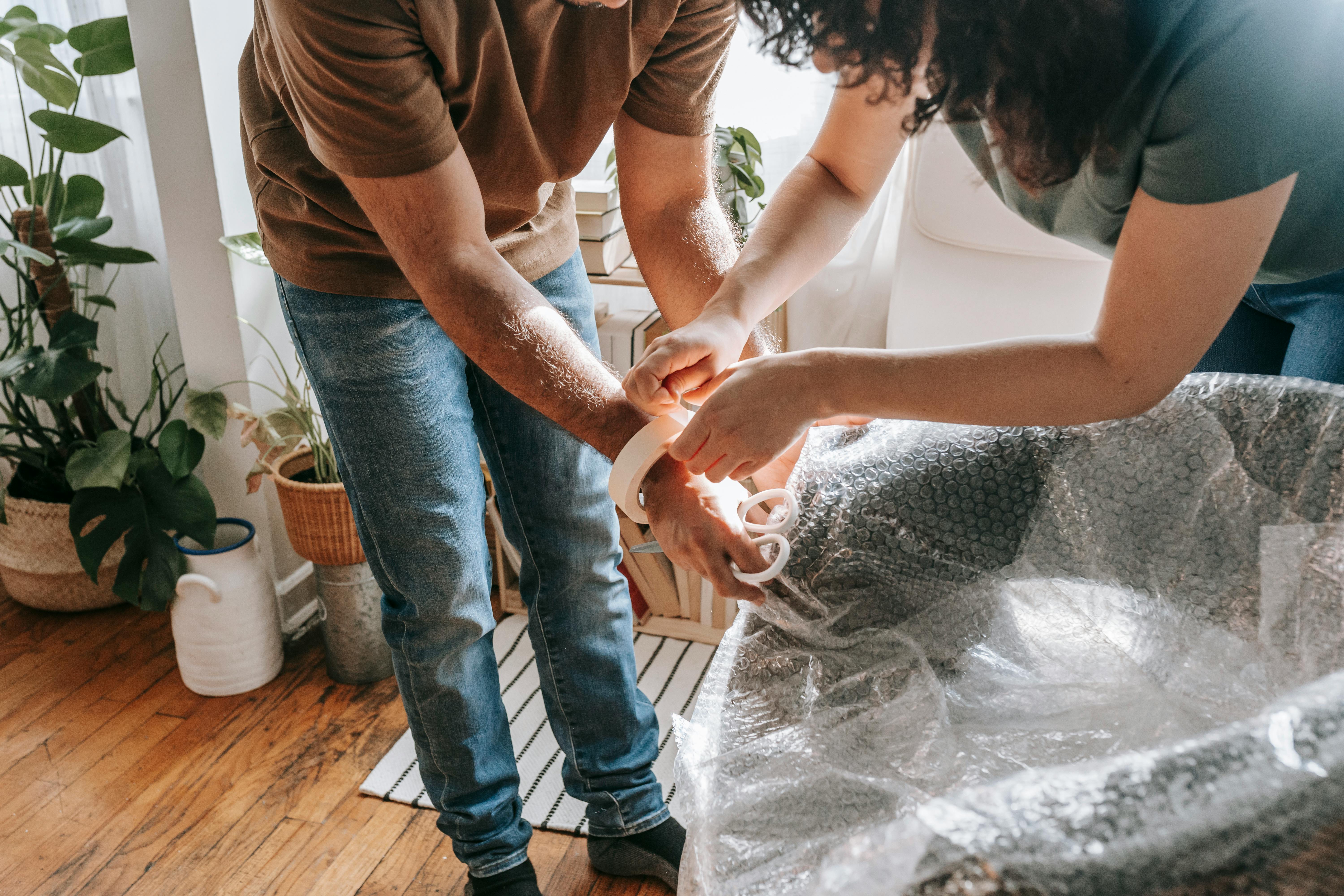 a couple wrapping a chair with plastic