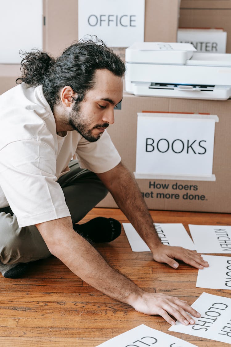 Man In White T-shirt Looking At Printed Labels For Boxes