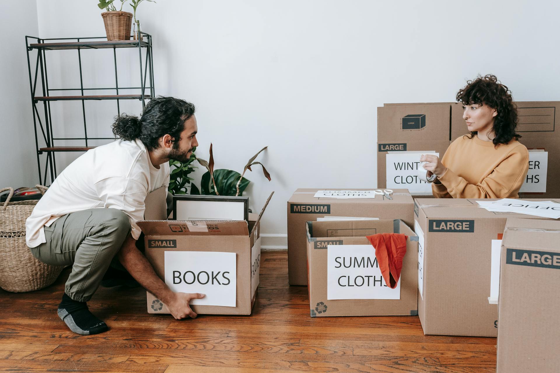 A Couple Packing Up Boxes With Labels