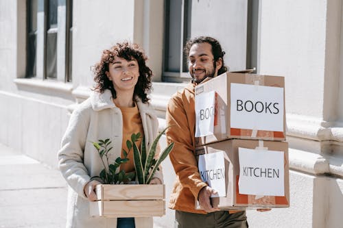 Free A Couple Moving Out Carrying Boxes And Plants Stock Photo