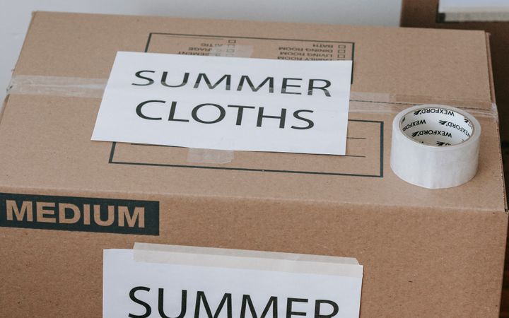 Labeled cardboard boxes for summer clothes ready for moving or storage, with packing tape and labels.